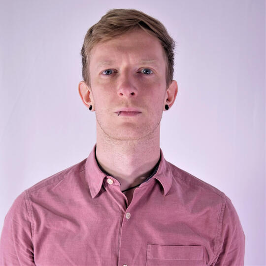 Headshot of Blonde Man wearing a Pink Shirt